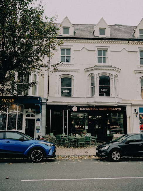 A white multi-story building with classic architectural details, housing the Botanica Babe Plants shop on the ground floor, which features large windows and a black sign with white lettering. In front